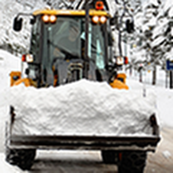 A snow plow from Dahme Construction clears a road in San Jose, pushing a large amount of snow.